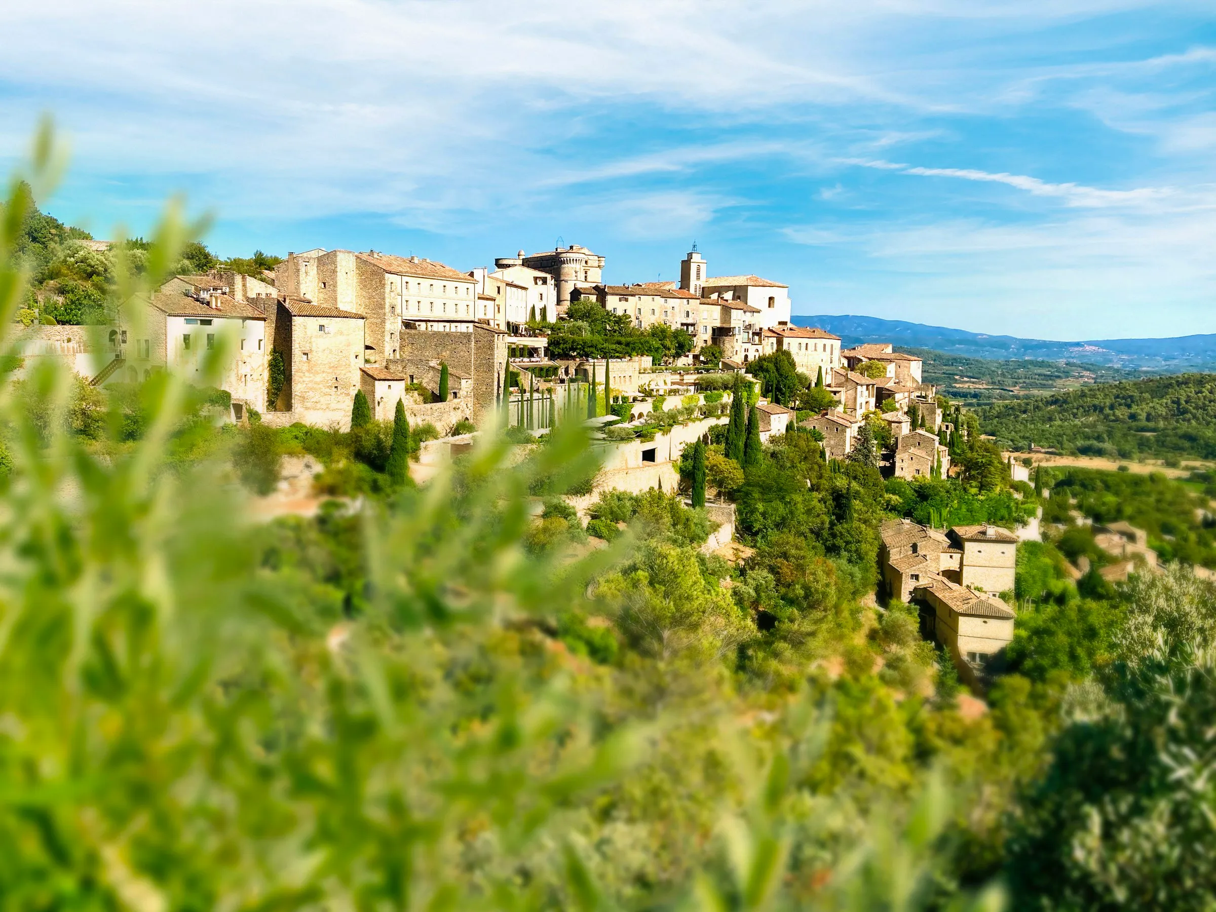 Bourg perché de l'arrière-pays, vu à travers des oliviers.